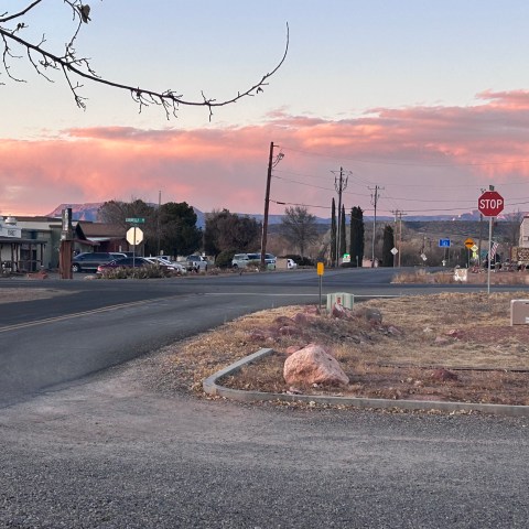 Small town street with sunset sky, mountains, and a stop sign in Cornville.